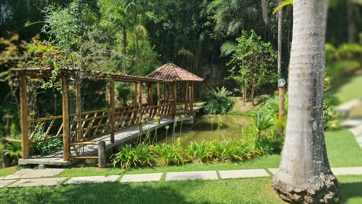 Jardim com pergolado de madeira e ponte